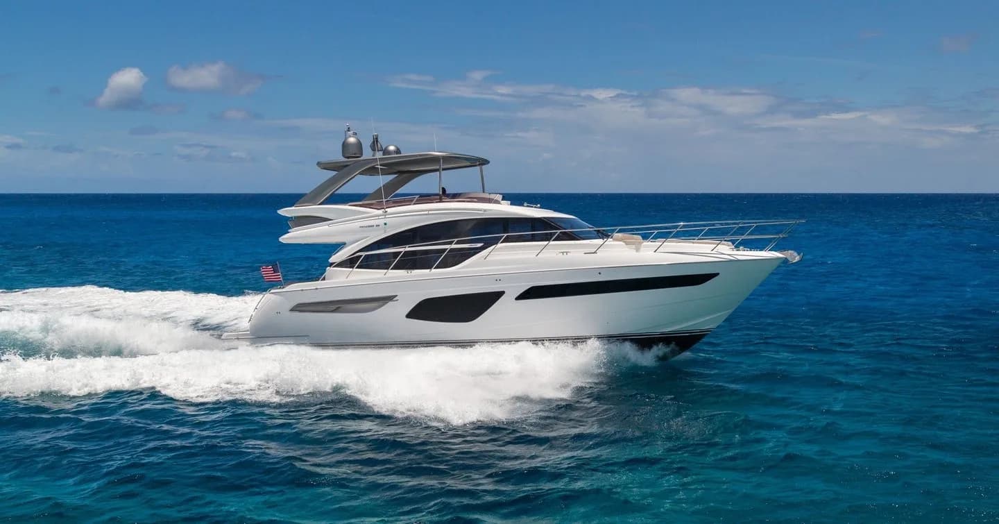 A white flybridge motor yacht under way on deep blue open water