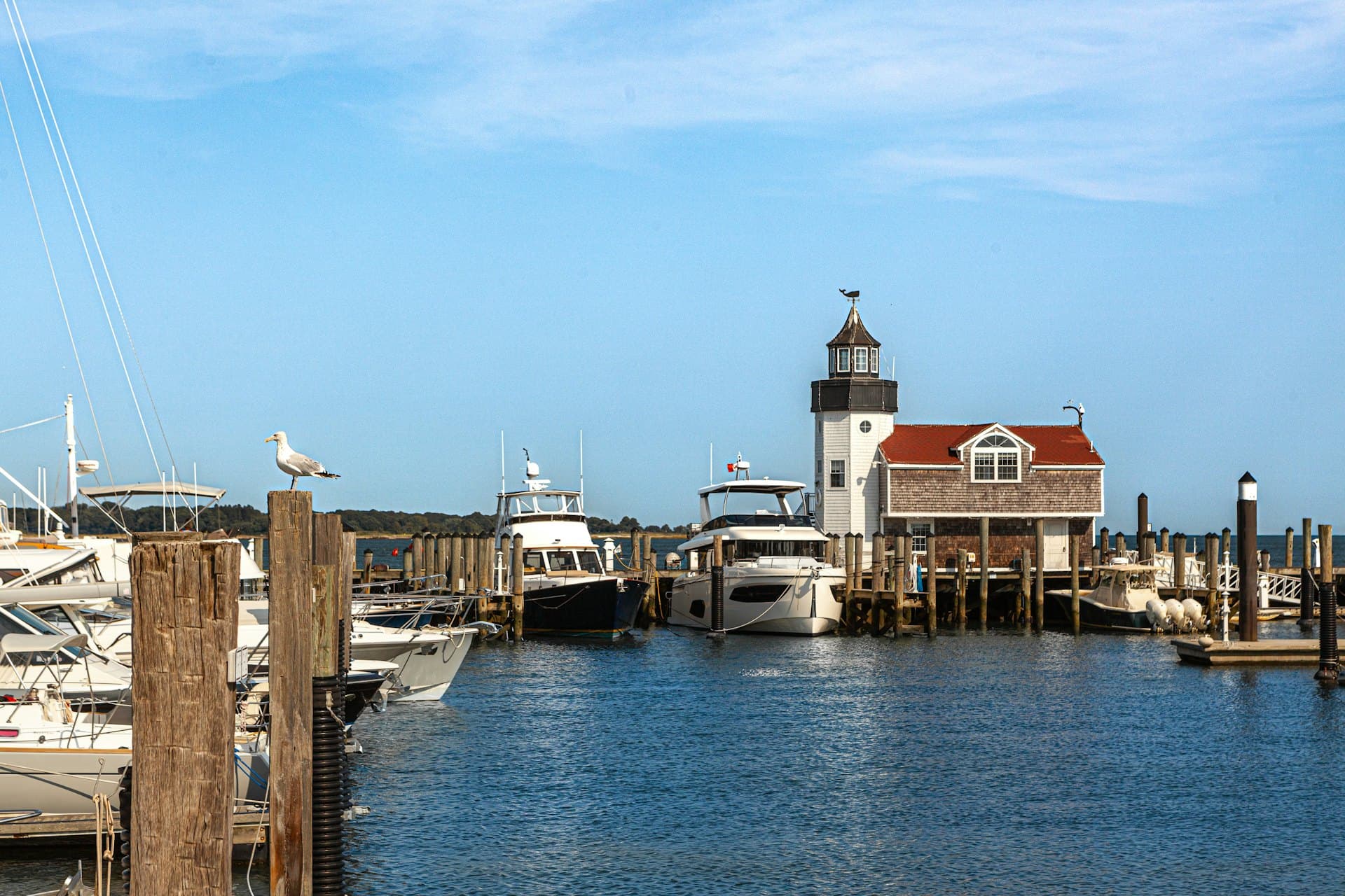 A shingled harbourmaster's building on its dock, boats alongside
